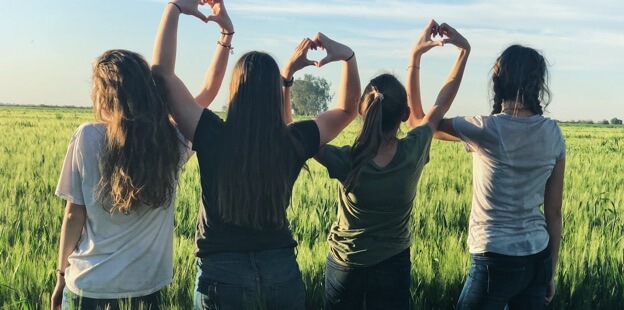 Young people standing together in unity, making heart shapes with their hands